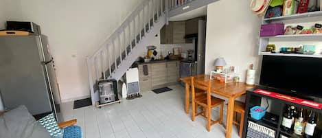 A compact living space with a kitchen, dining area, and a staircase leading to an upper level.