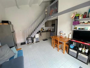 A compact living space with a kitchen, dining area, and a staircase leading to an upper level. - Detached holiday home with terrace, private garden, and air conditioning (Saint-Cyprien)