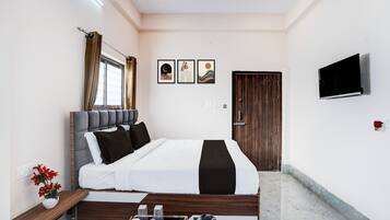 Une chambre à coucher moderne avec un lit, une table de chevet, un téléviseur, une œuvre d’art et une porte.