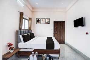 A modern bedroom with a bed, bedside table, TV, artwork, and a door. - Collection O Salori (Prayagraj)