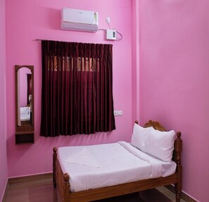 Une chambre avec un lit, un miroir, une fenêtre avec des rideaux et un appareil de climatisation.
