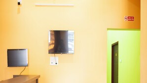 A reception area with a flat-screen TV mounted on the wall, a power outlet, and a no-smoking sign. - Sri Siva Shankara Inn (Tiruvannamalai)