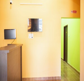 Un área de recepción con un televisor de pantalla plana montado en la pared, un enchufe y un letrero de no fumar.