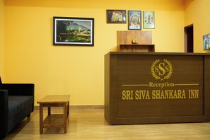 Una recepción con el nombre 'Sri Siva Shankara Inn' y un cuadro de un templo en la pared.