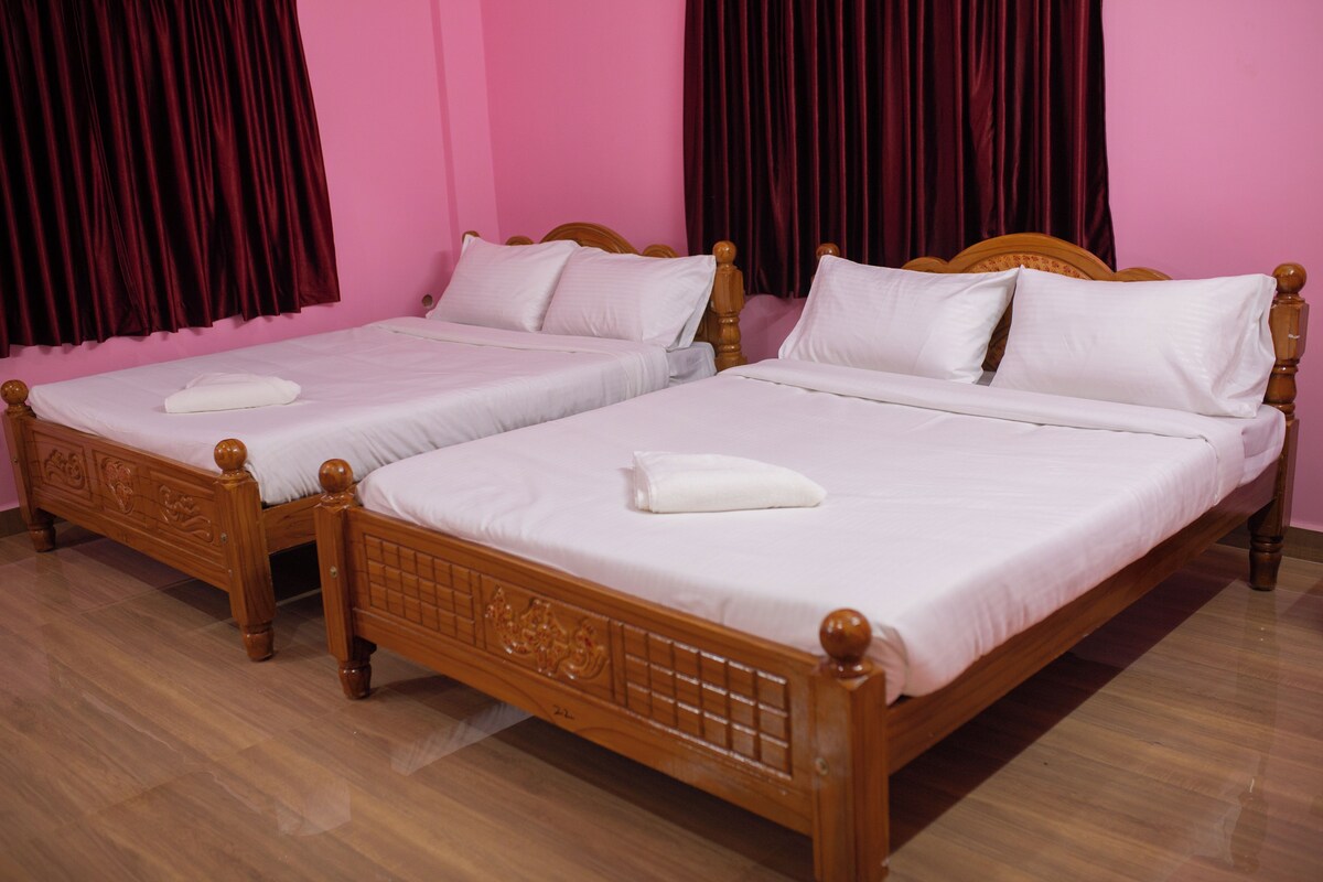 Two double beds with wooden headboards and footboards, white bedding, and a pink wall.