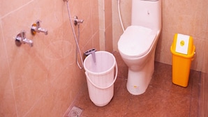 A bathroom with a toilet, a shower, and a trash bin. - Sri Siva Shankara Inn (Tiruvannamalai)