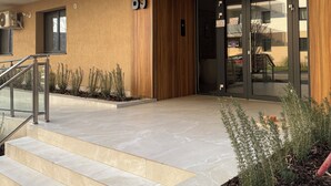 A modern building entrance with a wooden facade, a glass door, and a sign indicating room number B5. - Green Pine Studio Hils Brauner - Free Parking - Nearby Metro Station (București)
