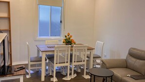 Un comedor con candelabro, una mesa con sillas, un sofá y una ventana con persianas.