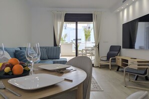 A dining area with a table set for two, a sofa, and a TV in a modern living space. - SUNNY HILLS dream apartment (Finestrat)