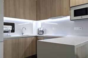 A modern kitchen with wooden cabinets, a built-in microwave, and a coffee maker. - SUNNY HILLS dream apartment (Finestrat)