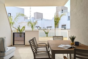 A balcony with a table, chairs, and a sofa. There are plants and a view of buildings in the background. - SUNNY HILLS dream apartment (Finestrat)
