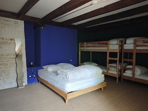 Et værelse med en enkelt seng, køjeseng og en væg med et unikt design.
