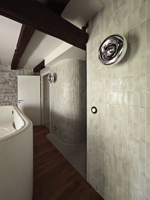 A bathroom with a bathtub, a shower, and a tiled wall.