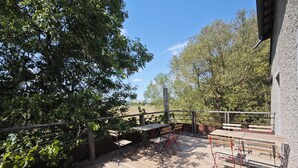 An outdoor deck with wooden flooring, metal railings, and foldable tables and chairs. - Domaine du Moulin Français - Along the River (Champougny)