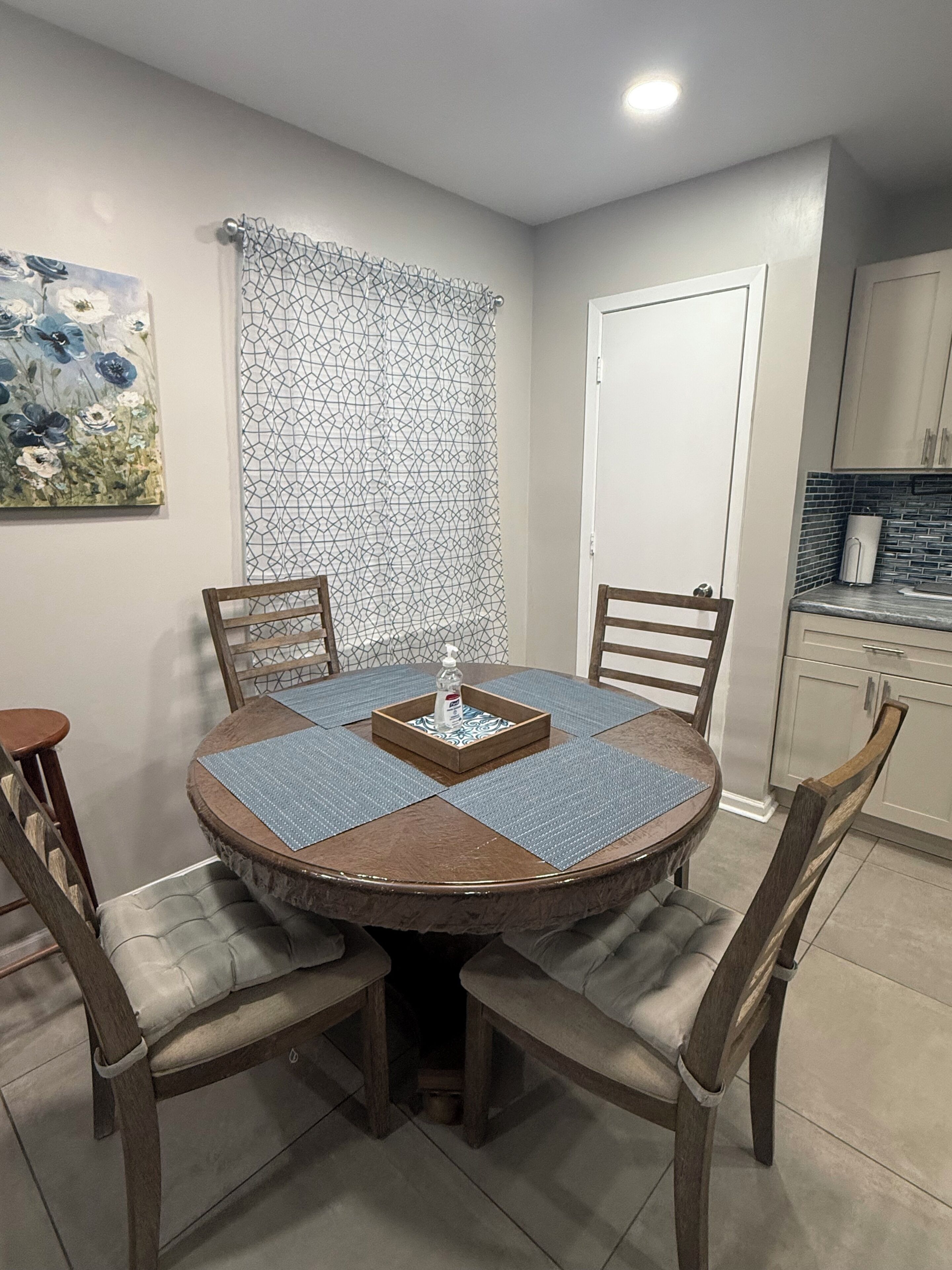A dining area with a round table, four chairs, and a decorative tray.