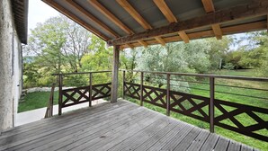 A wooden deck with a metal railing, overlooking a grassy area with trees. - Domaine du Moulin Français - Outdoors (Champougny)