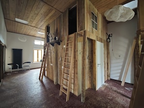 Een kamer met houten wanden, een ladder en een hanglamp.