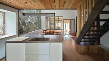 Une cuisine moderne dotée d’un îlot central, de planchers en bois et d’un escalier menant à un niveau supérieur.