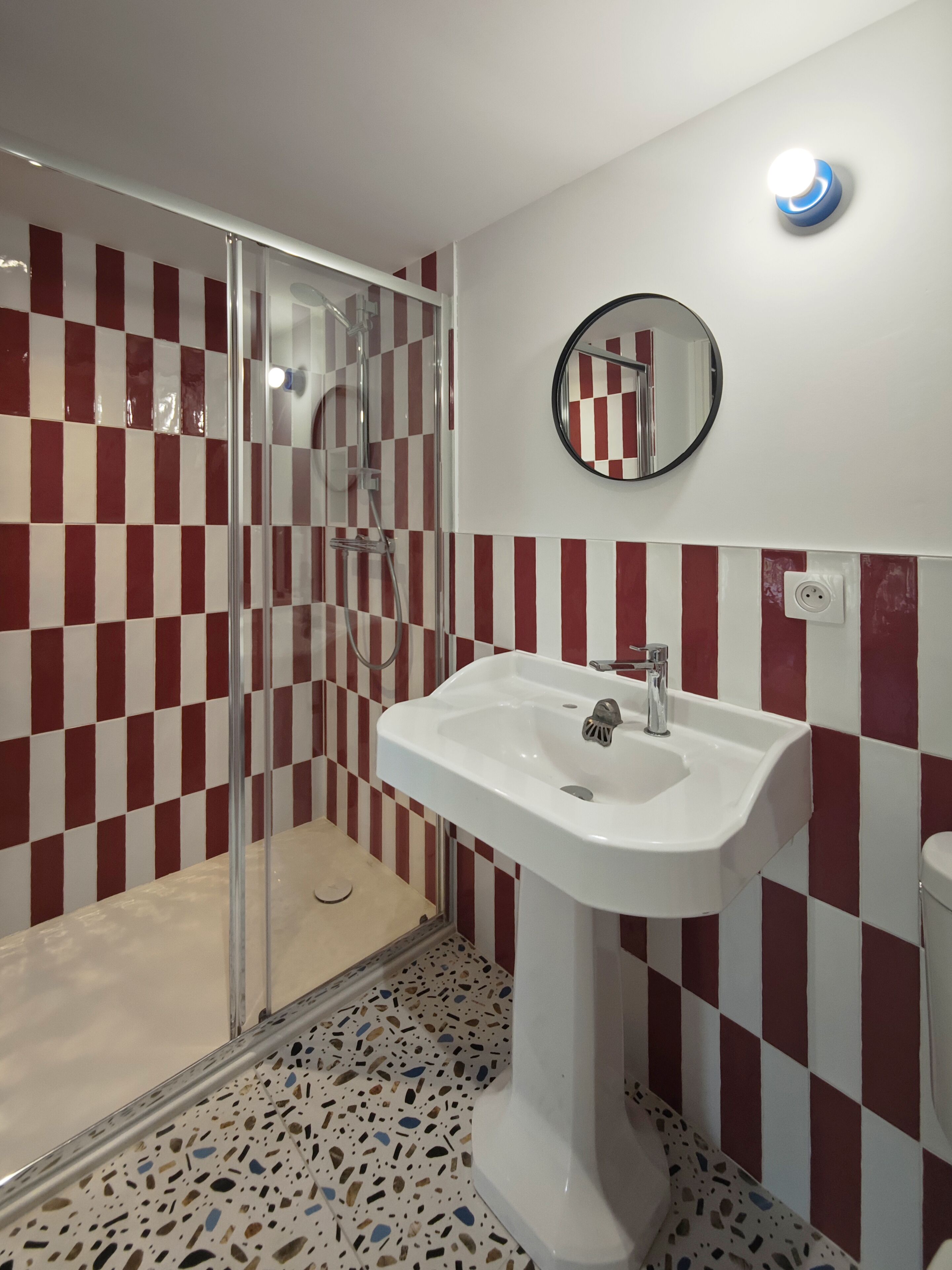 Ein Badezimmer mit Dusche, Waschbecken und Spiegel.