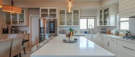 A modern kitchen with a central island, built-in cabinets, and a hanging light fixture.