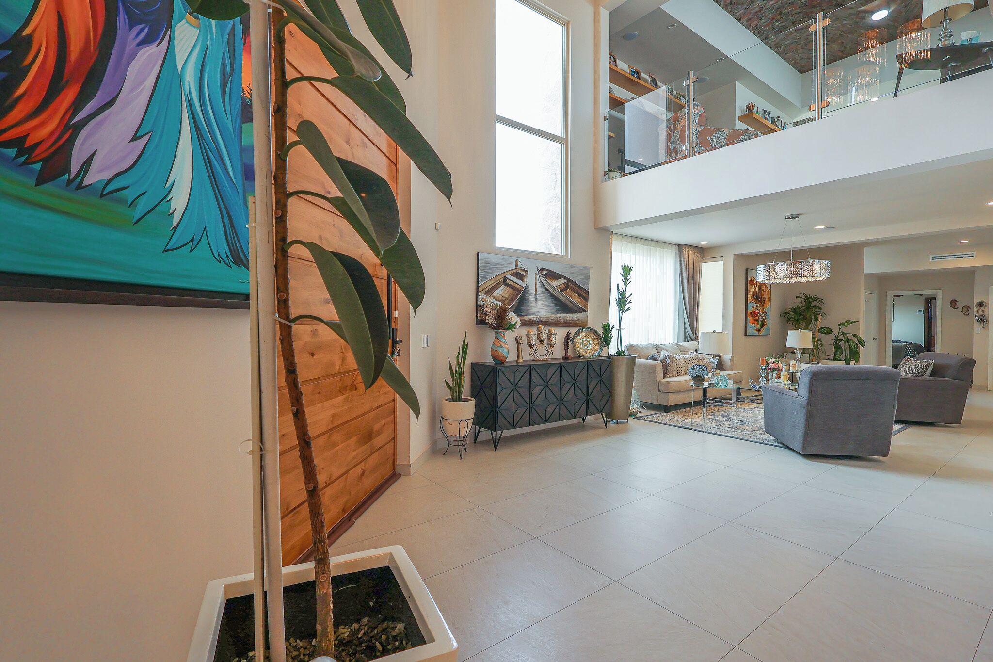 Un hall espacioso con diseño moderno, que incluye una planta grande, obras de arte y una zona de estar con sofás.