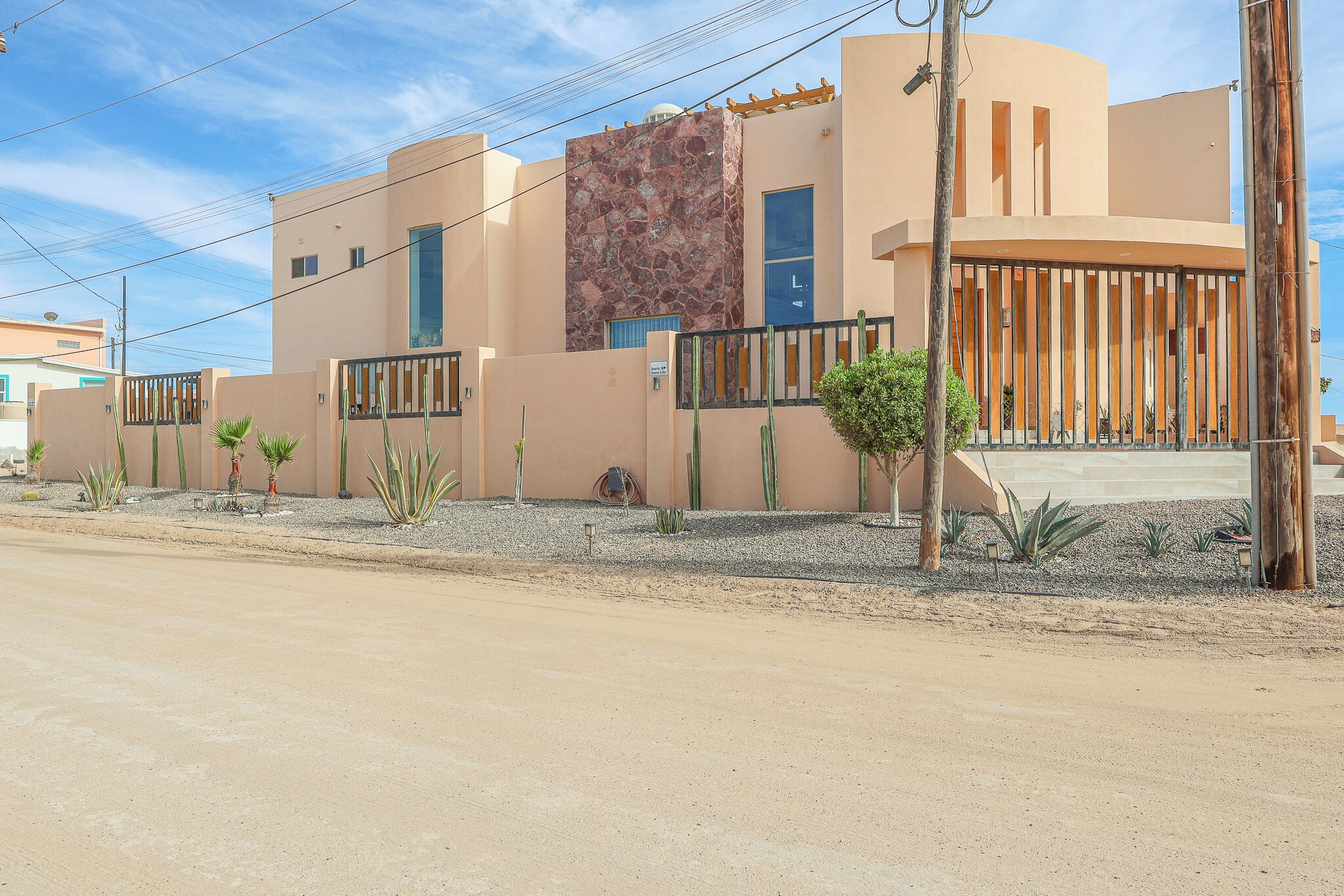 Un bâtiment moderne doté d’un toit plat, d’une façade en pierre et d’une entrée fermée par un portail.
