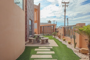 A courtyard with a stone bench, a cactus, and a paved walkway. - Las Mareas 53 | Luxury Coastal Retreat | Walk to Beach (Puerto Peñasco)