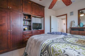 Ein Schlafzimmer mit einem Bett, einem Fernseher, Holzausbau und einer Tür zu einem weiteren Raum.
