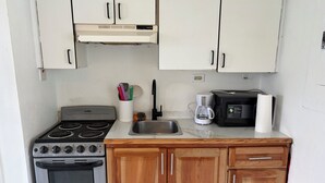 Una cocina compacta con estufa, horno, pileta y alacenas de madera.