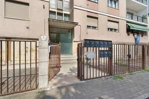 Een hek toegang tot een gebouw, met een brievenbus en een fiets ervoor geparkeerd.