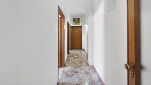 Ein Korridor mit Steinplattenboden, Holztüren und einem farbenfrohen Kunstwerk an der Wand.