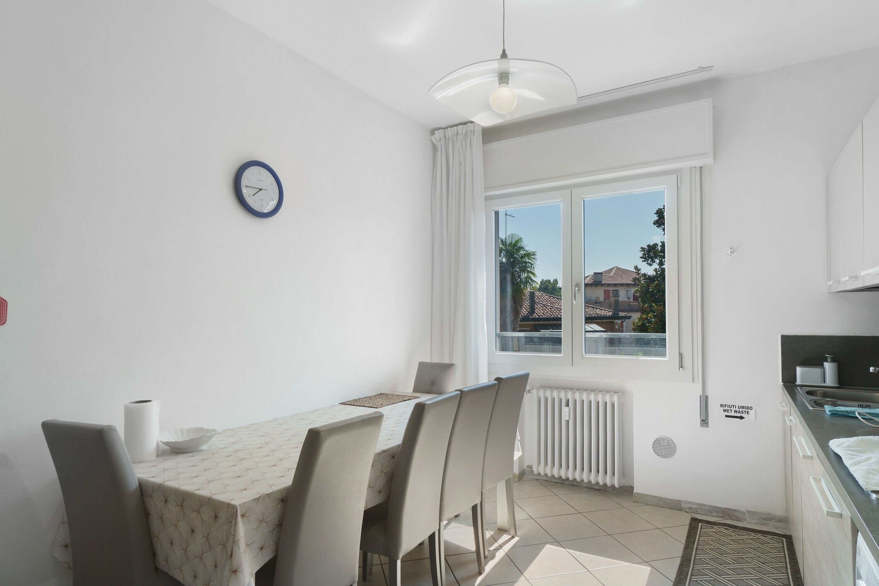 A modern kitchen with white cabinets, a built-in oven, and a window with a view of the outside.