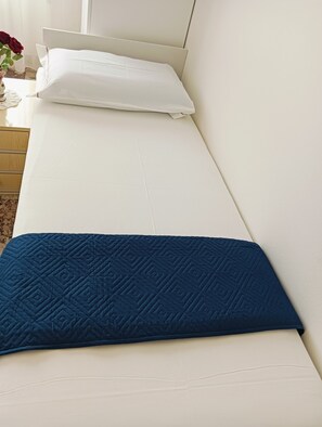 A bed with a white mattress and a blue quilted pillow. - Aaron Guest House - 4-Bedroom Apartment in Marghera (Venice)