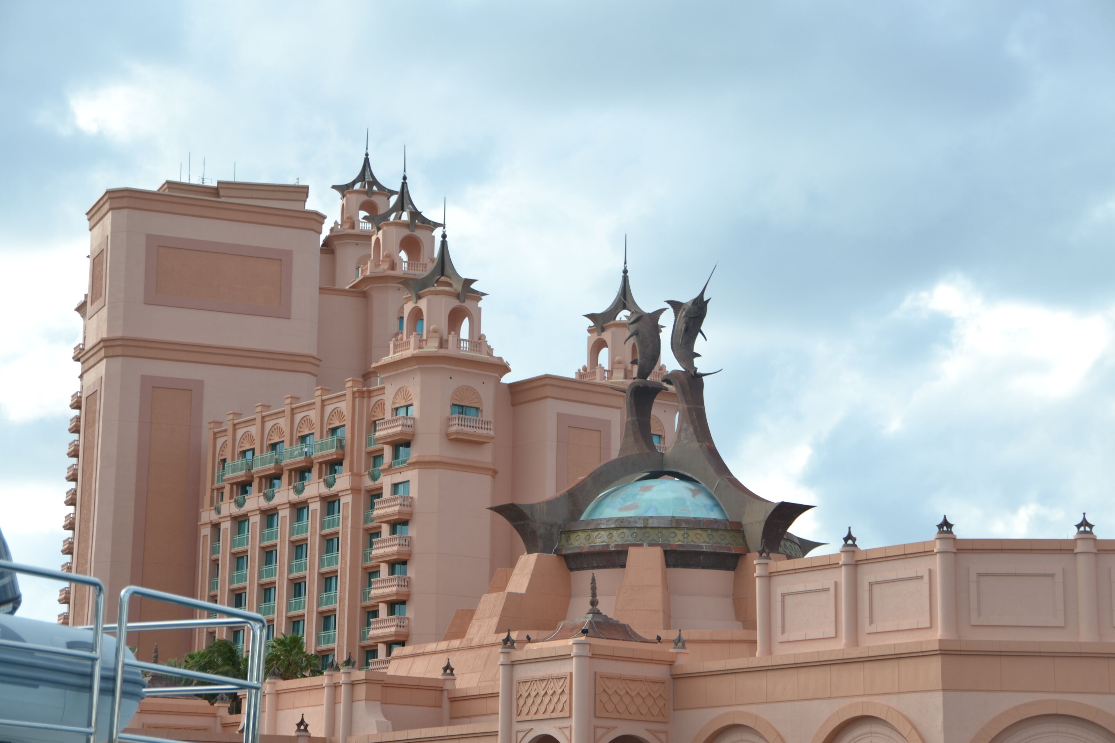 A large, multi-story hotel with a distinctive pink facade, multiple balconies, and a central dome structure.