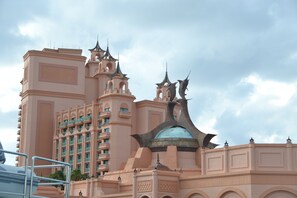 A large, multi-story hotel with a distinctive pink facade, multiple balconies, and a central dome structure. - Premium 1-bedroom condo with full access to Atlantis (Paradise Island)
