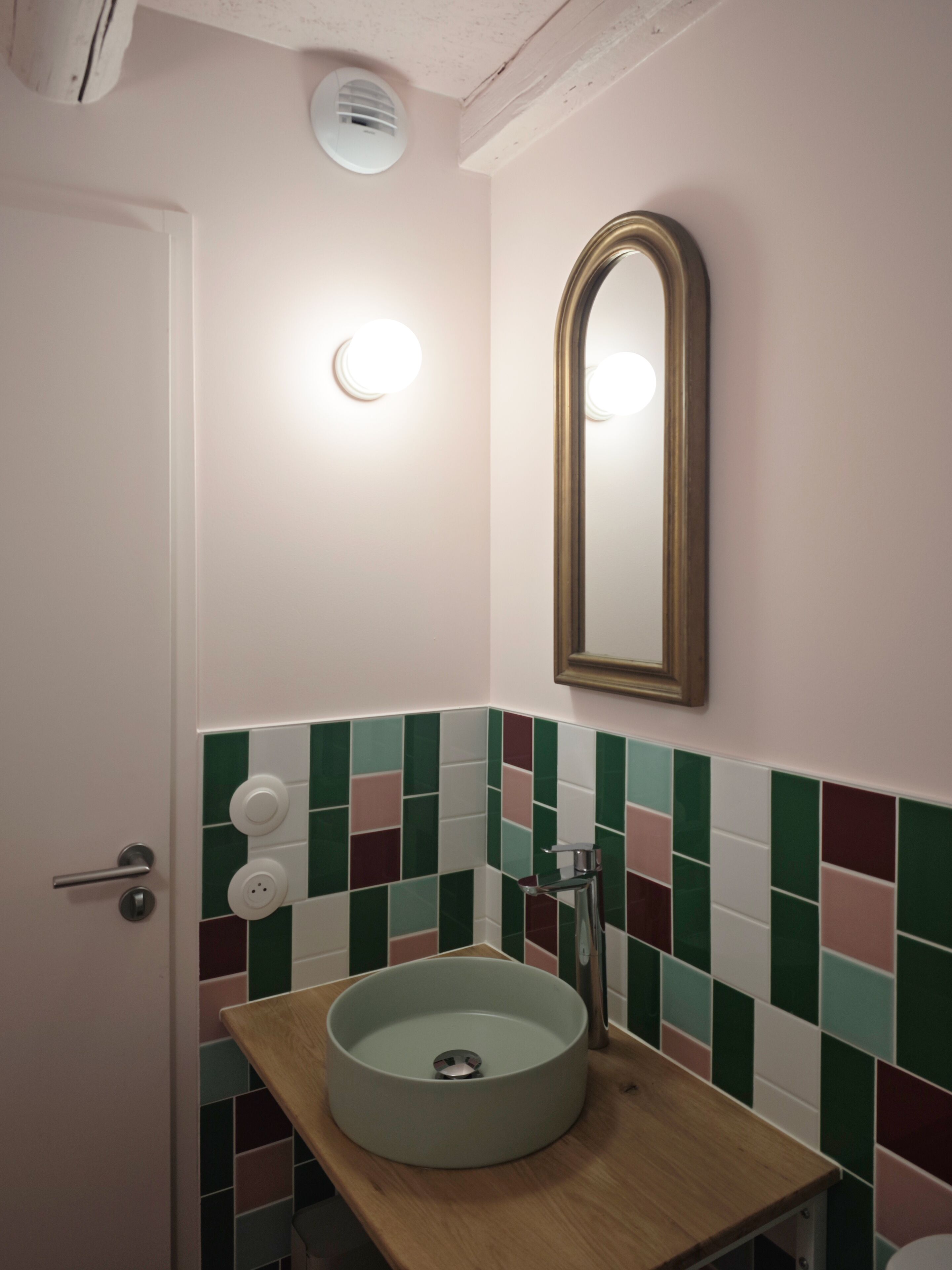 Une salle de bain avec un lavabo rond, un miroir et une porte.