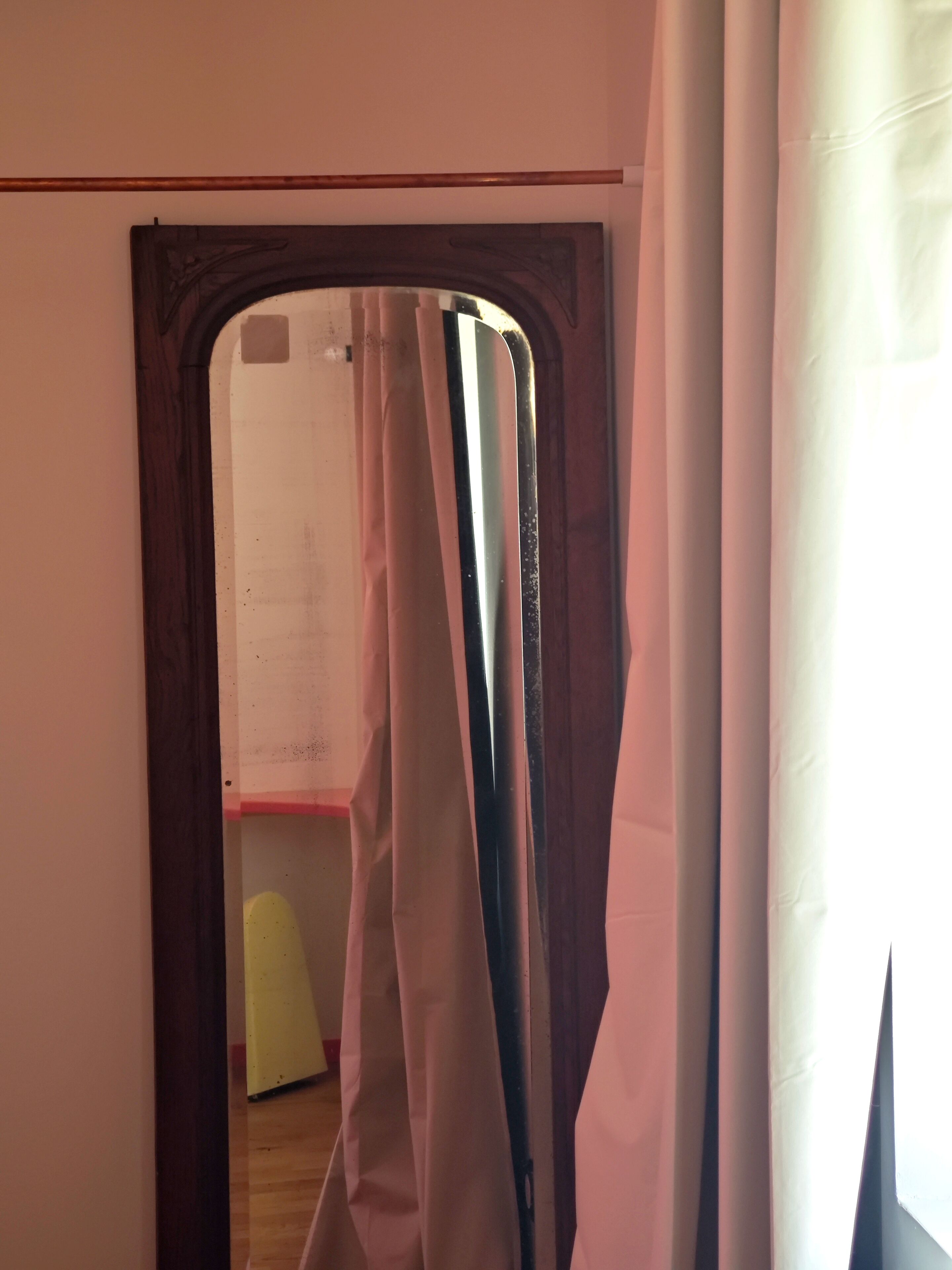 A doorway leading to a room with a white wall and a wooden floor.
