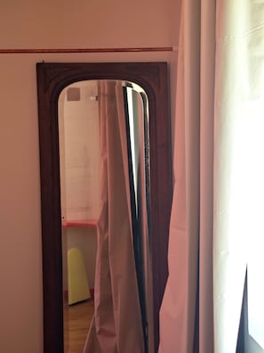 A doorway leading to a room with a white wall and a wooden floor.