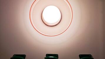 Un luminaire mural de forme circulaire, doté de trois interrupteurs verts situés en dessous.