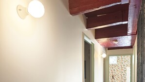 Un corridoio con pavimento in legno, un lampadario a parete e una porta che dà su un'altra stanza.
