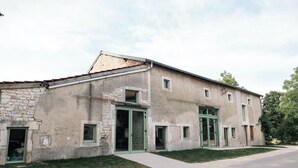 Un bâtiment à deux étages, doté d’une façade en pierre, de nombreuses fenêtres et d’une allée pavée.