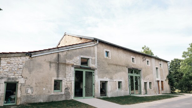 Un edificio a due piani con facciata in pietra, diverse finestre e un vialetto lastricato.