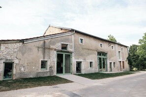 A two-story building with a stone facade, multiple windows, and a paved driveway.