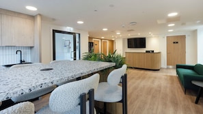 Eine moderne Küche mit einer Granit Arbeitsplatte und einer Bar, einem hölzernen Empfangstresen und einem grünen Sofa in einer Lounge-Ecke.
