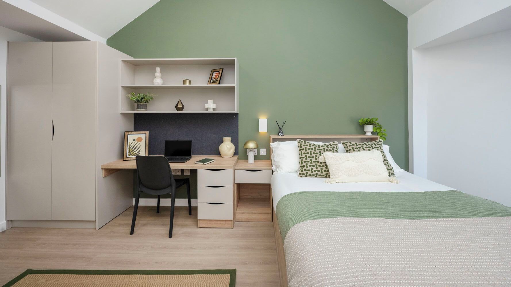 Un dormitorio con cama, escritorio con silla, armario y estante con objetos decorativos.