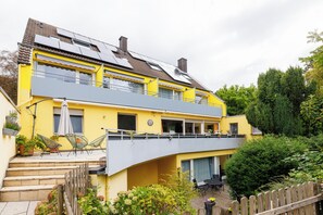 Een gebouw met twee verdiepingen, een balkon, zitplaatsen buiten en een tuin.