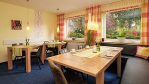 Ein Essbereich mit Holztischen und -stühlen, einem Buffet und Blick auf Grünflächen.