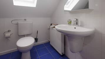 A bathroom with a toilet, a sink, a radiator, and a window.