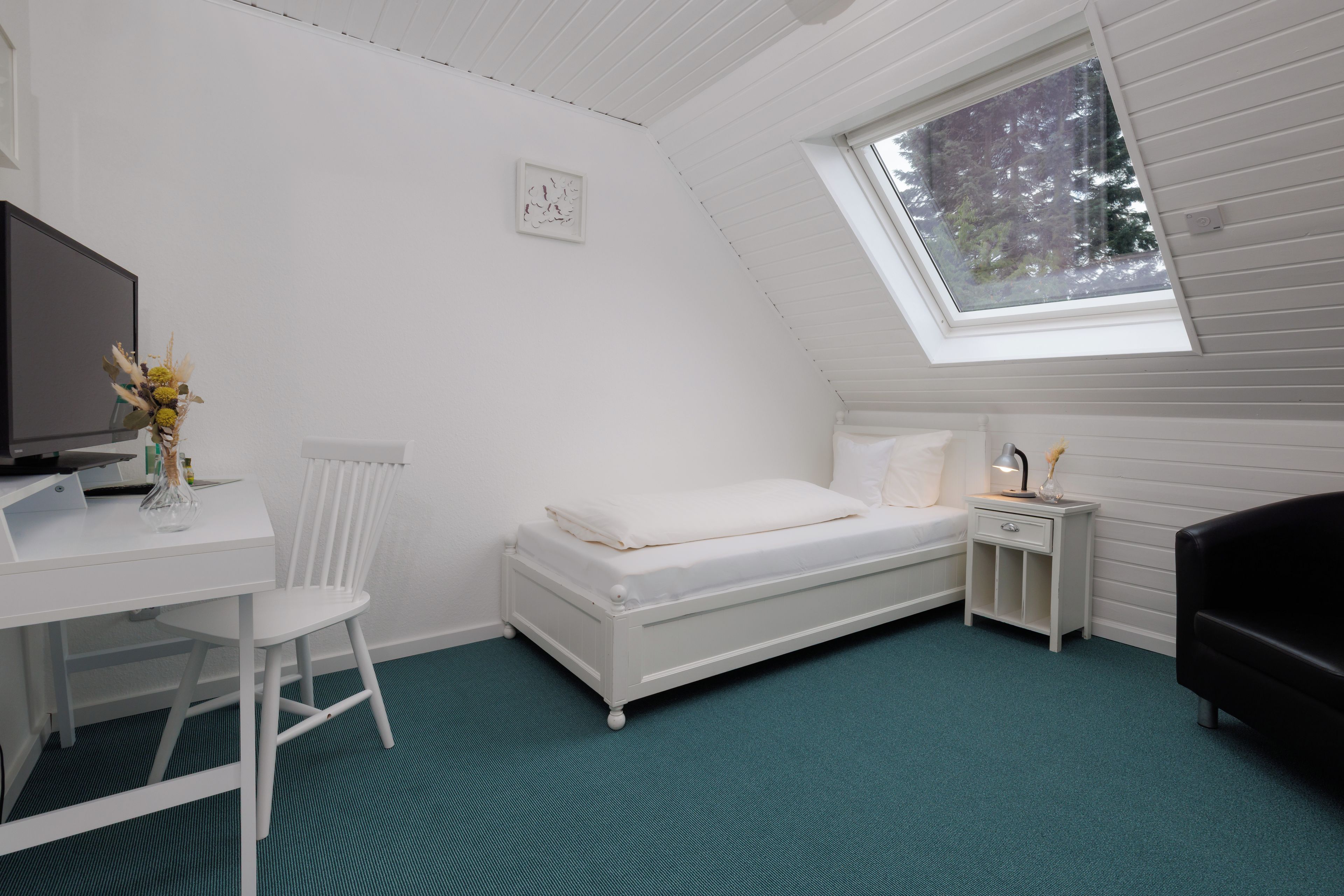 Eine kleine, weiße Einzimmerwohnung mit schrägem Dach und einem Dachfenster.