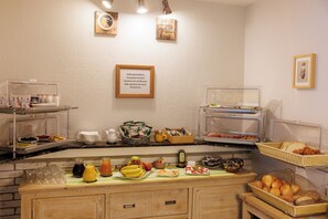 A buffet setup with various food items, a coffee station, and a sign indicating the availability of specialty coffee and other services. - Hotel Haus Mariandl (Düsseldorf)
